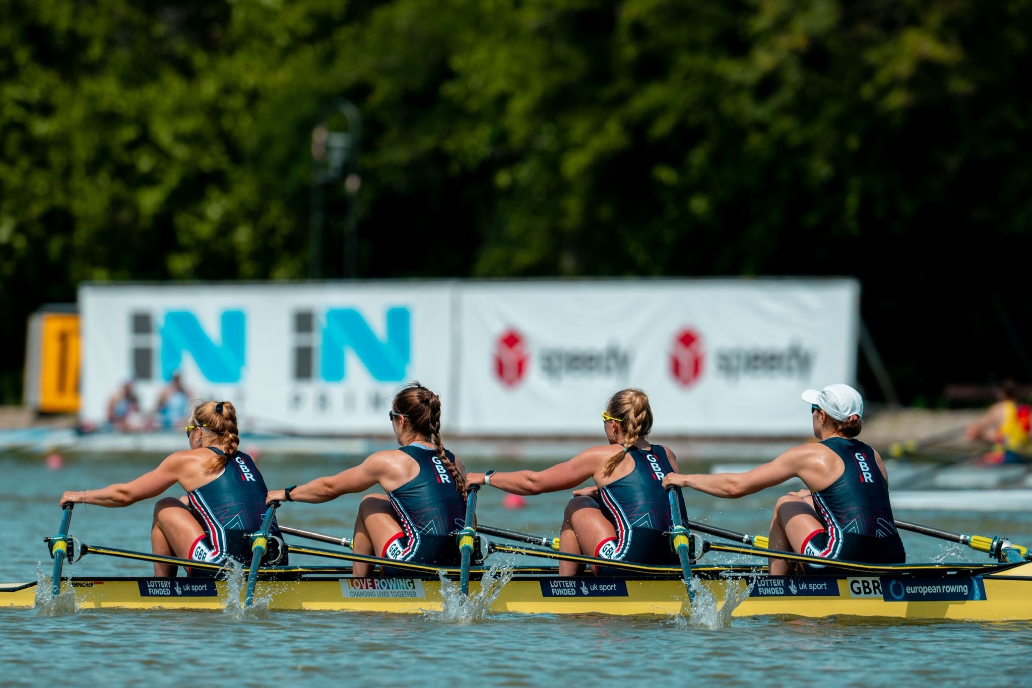 Four rowers in a long boat racing on a river