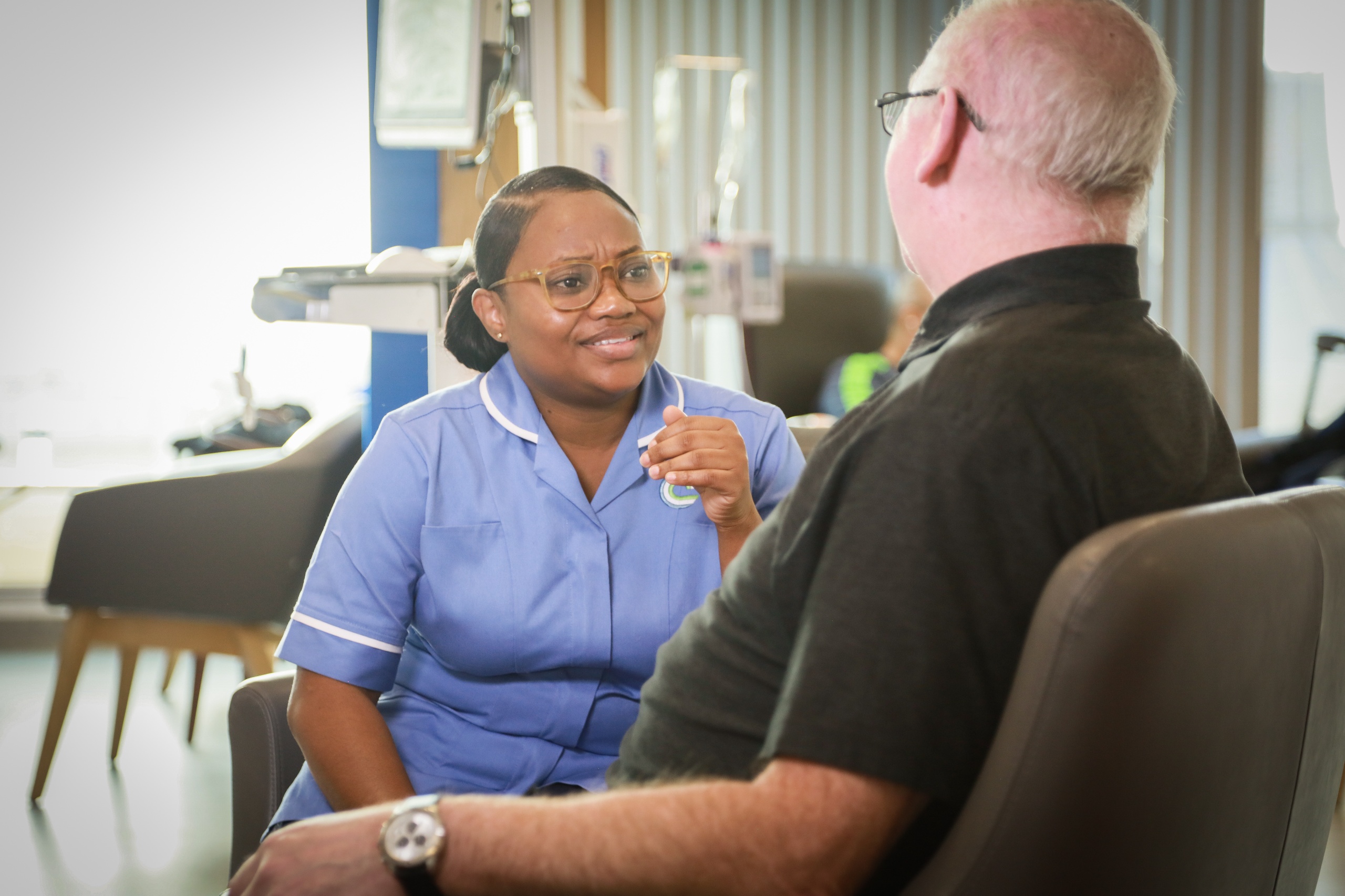 Hospital staff member in blue nursing uniform with patient
