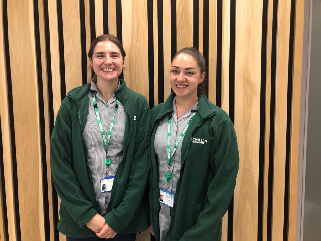 Two nurses in blue striped uniforms and dark green fleeces
