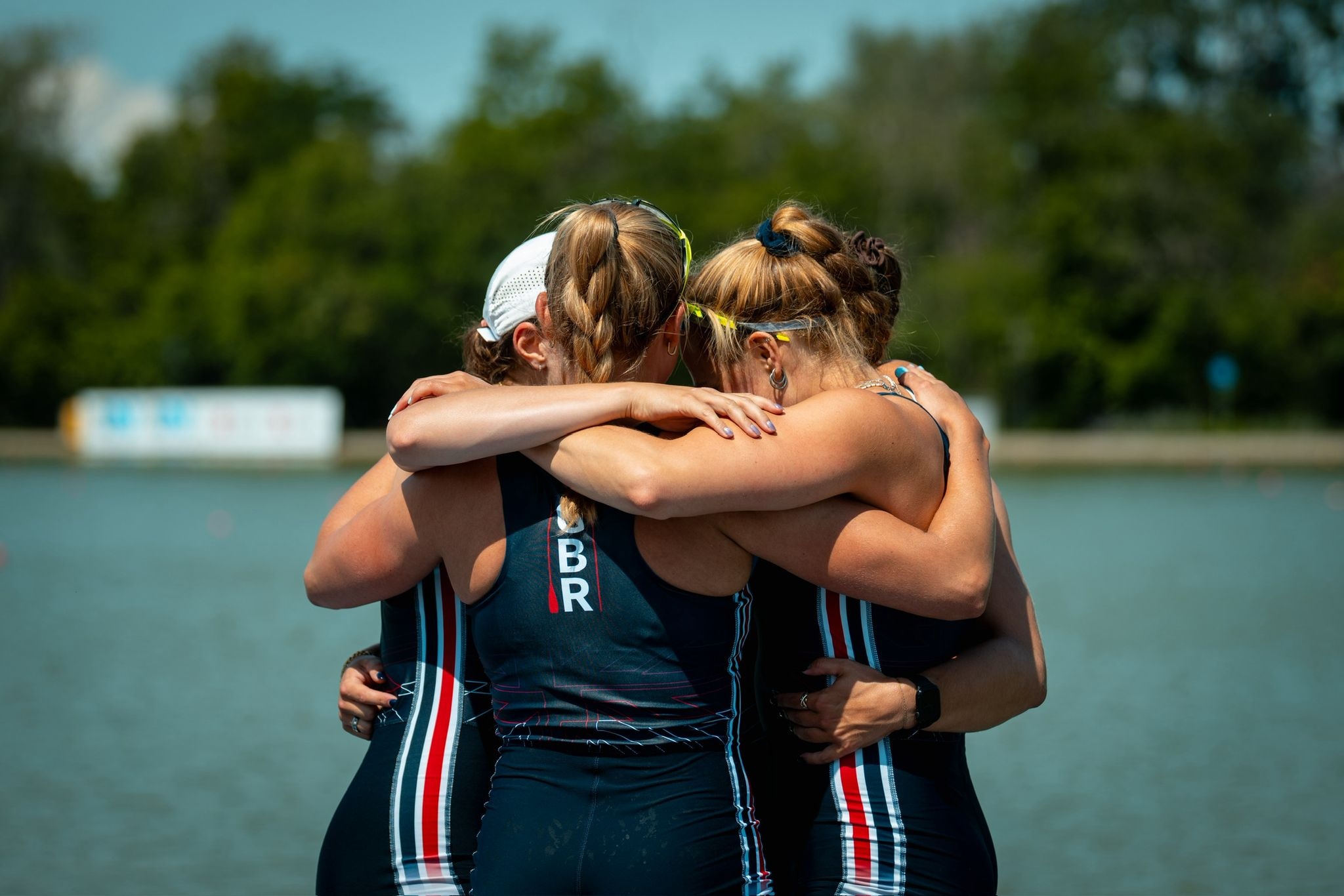 Three rowers hugging by the water