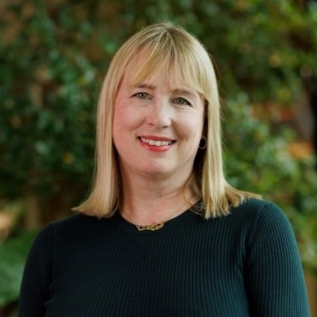 Liz has shoulder length dark blonde hair with a fringe