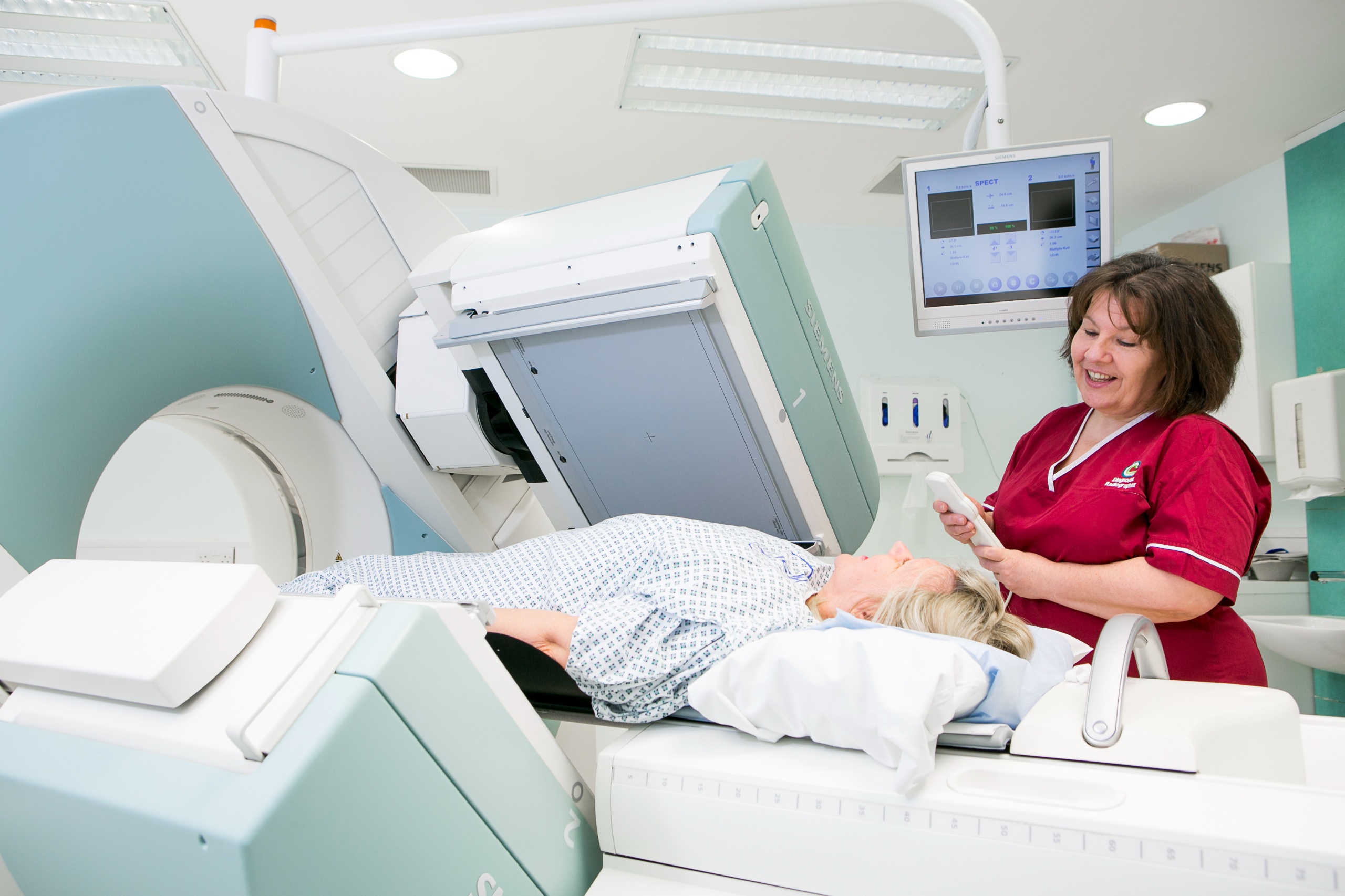Person in hospital gown lying on scanner bed. The scanner has rectangular parts that take images of the body