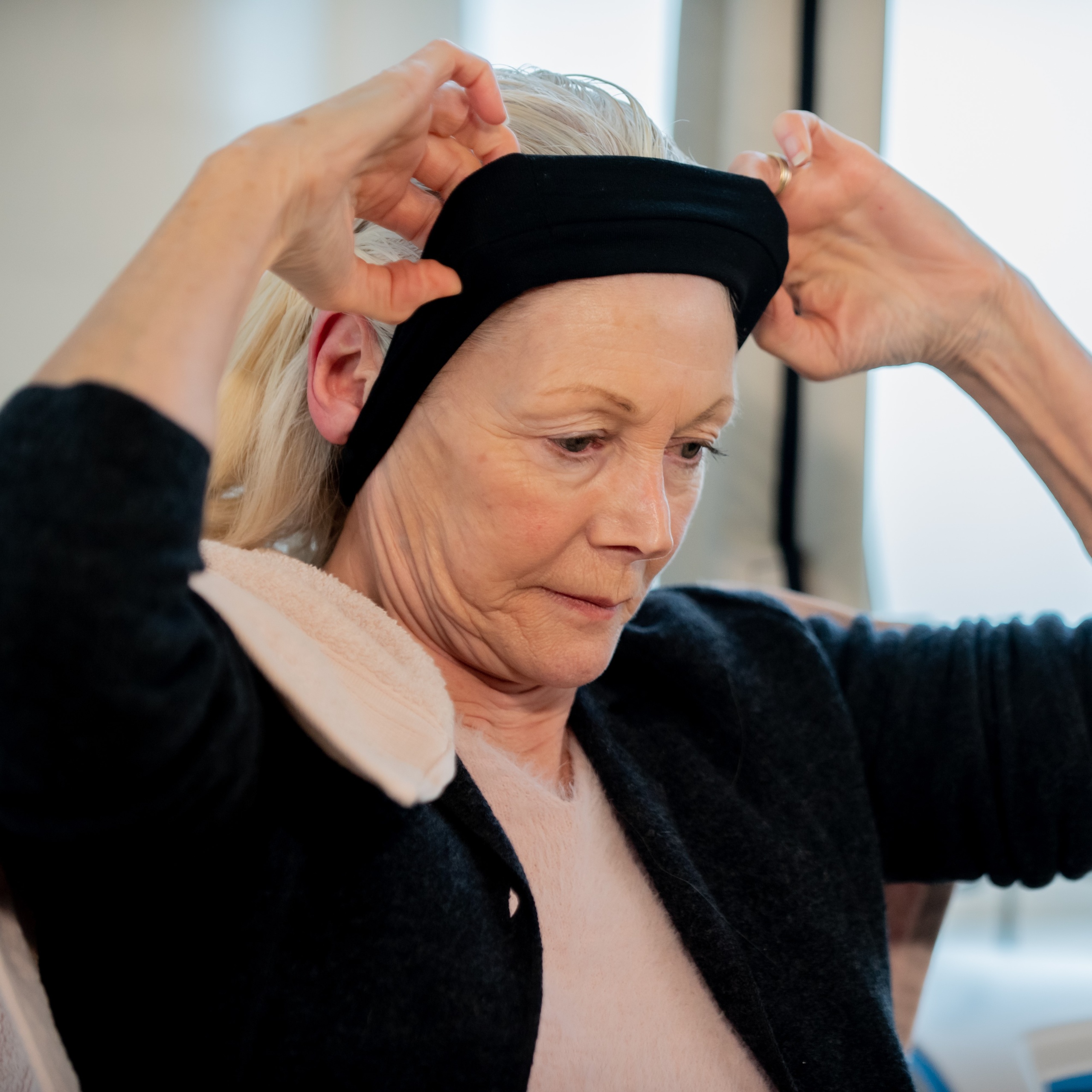 A woman puts a stretchy black headband around her head to keep her hair back before she puts on the cool cap