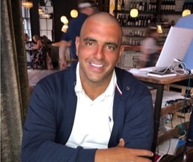 Aaron is sitting in a restaurant and smiling